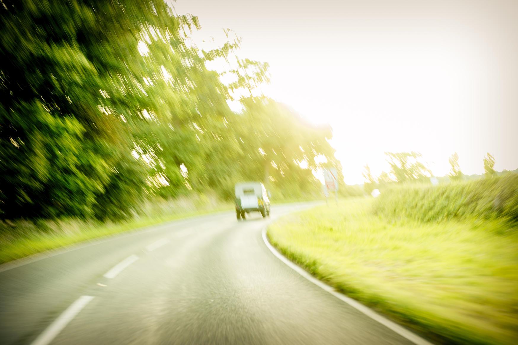 Bilvei omringet av grønt gress og trær. foto